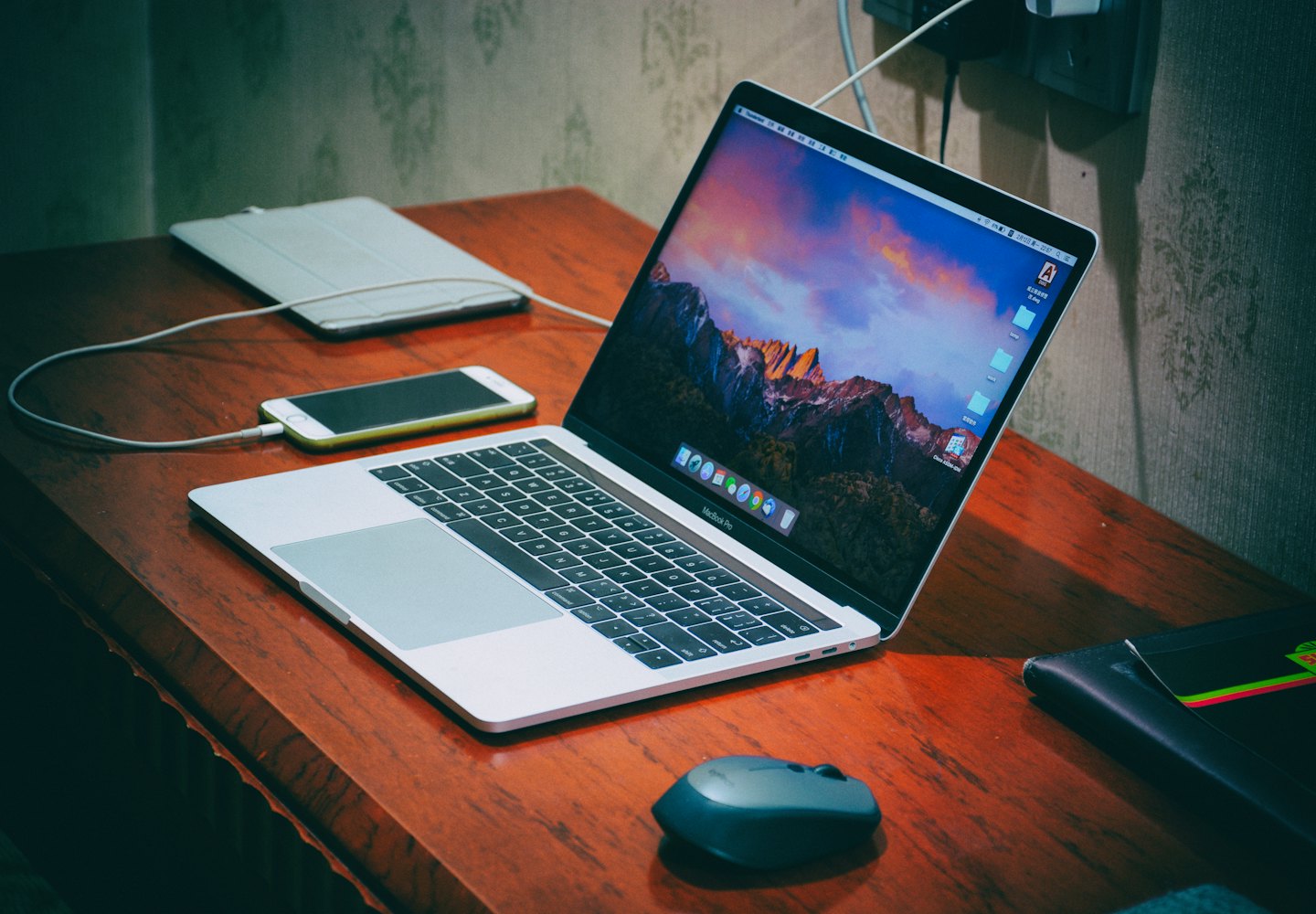 Laptop con sfondo di montagna su una scrivania di legno con telefono e tablet.